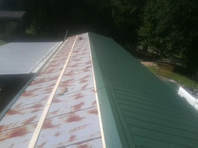Old rusted panels beside newly installed green metal roofing — Wind Damage Roof Repair by Roofing Brothers in Leck Kill