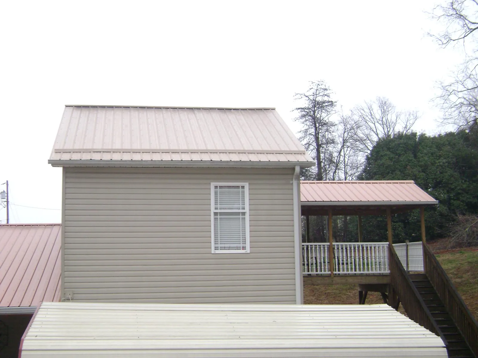 Tan metal roofs on a two story addition and attached porch, from a Roof Replacement job in Leck Kill