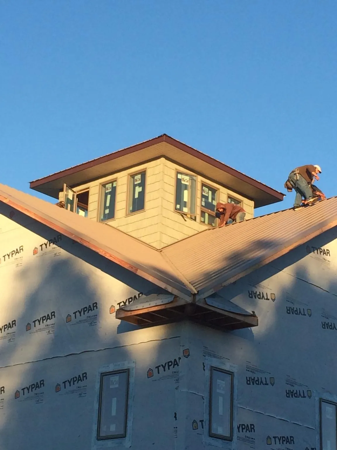 Roofers working around a rooftop cupola on a new metal roof at sunset — Roof Waterproofing in Leck Kill by Roofing Brothers